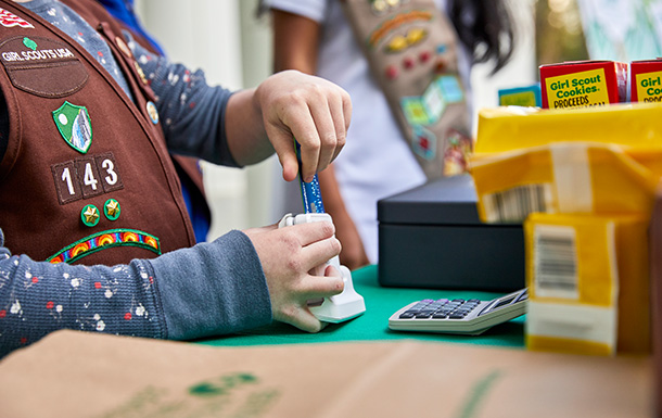 Girl Scout uses a credit card reader at a cookie booth