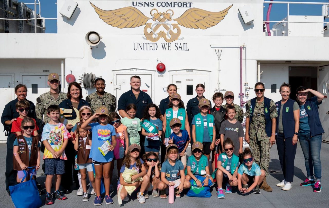 Terra Gray poses with Girl Scouts and other volunteers on the deck of the USS Comfort