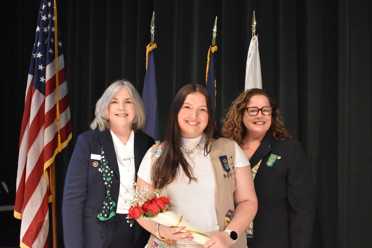 Girl Scout scholarship recipient at an awards ceremony with adult volunteers